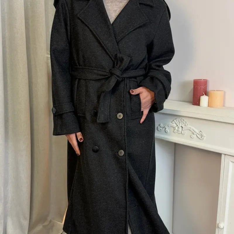 Questo cappotto doppiopetto presenta chiusura a bottoni, cintura integrata e pratiche tasche, rivelando un'eleganza raffinata e una versatilità pratica.