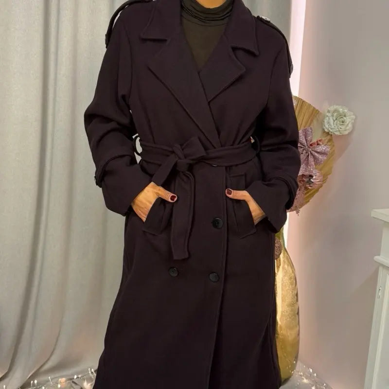 Questo cappotto doppiopetto presenta chiusura a bottoni, cintura integrata e pratiche tasche, rivelando un'eleganza raffinata e una versatilità pratica.