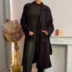 Questo cappotto doppiopetto presenta chiusura a bottoni, cintura integrata e pratiche tasche, rivelando un'eleganza raffinata e una versatilità pratica.